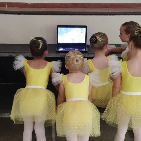 Young ballerinas watching ballet dance on laptop