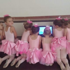 Young ballerinas watching ballet dance on laptop