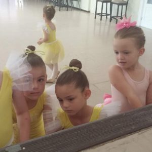 Young ballerinas watching ballet dance on laptop